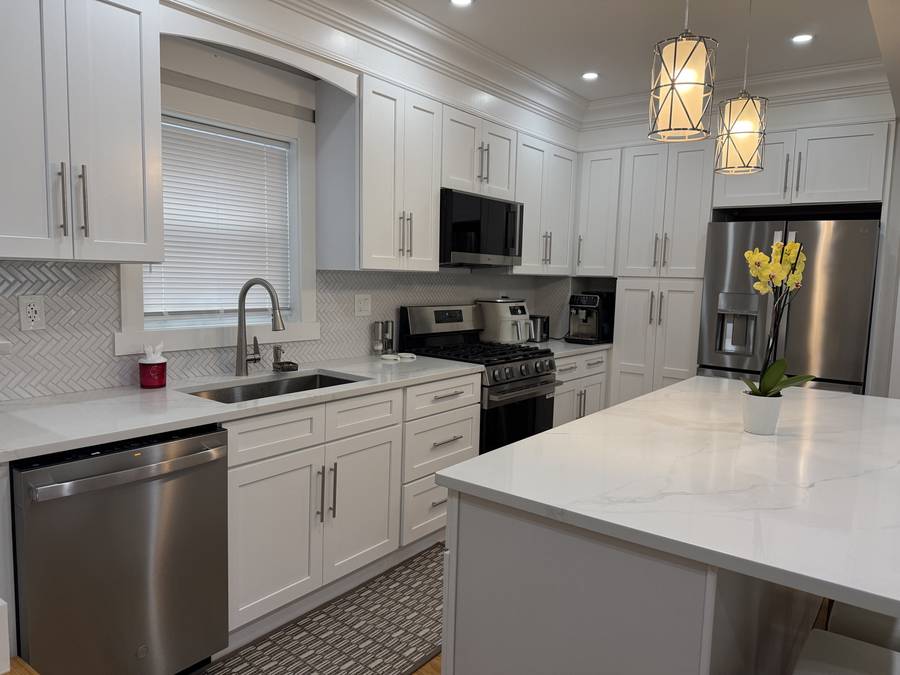 White shaker kitchen with quartz island, pendants and stainless appliances — Nexus Pro Construction