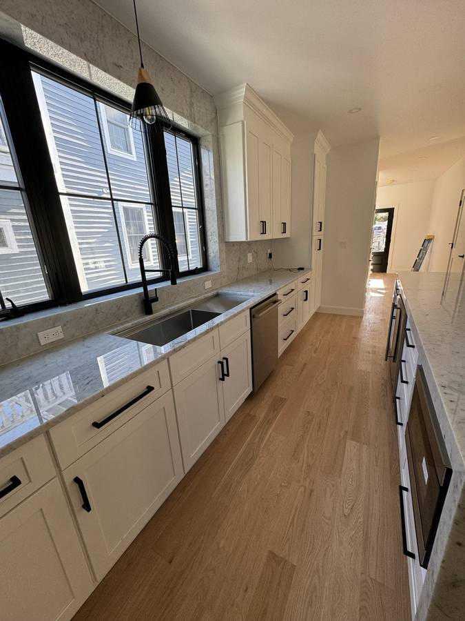 Galley kitchen with marble backsplash, black-frame windows and oak floor — Nexus Pro Construction